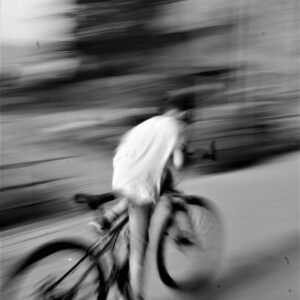 Blurred image of a cyclist riding fast in Tbilisi, Georgia, captured in grayscale.