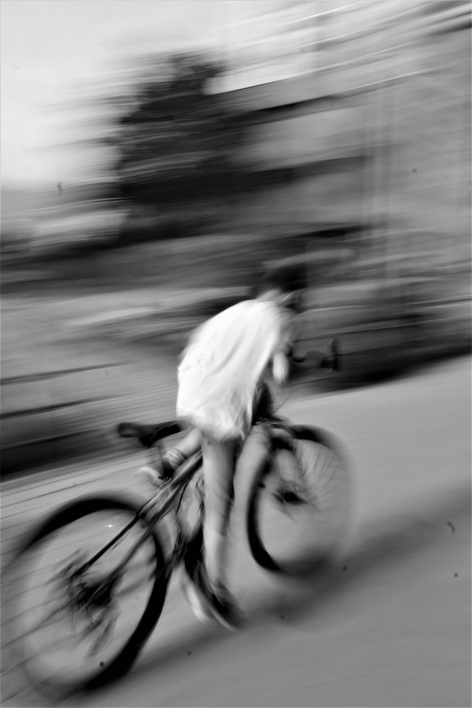 Blurred image of a cyclist riding fast in Tbilisi, Georgia, captured in grayscale.